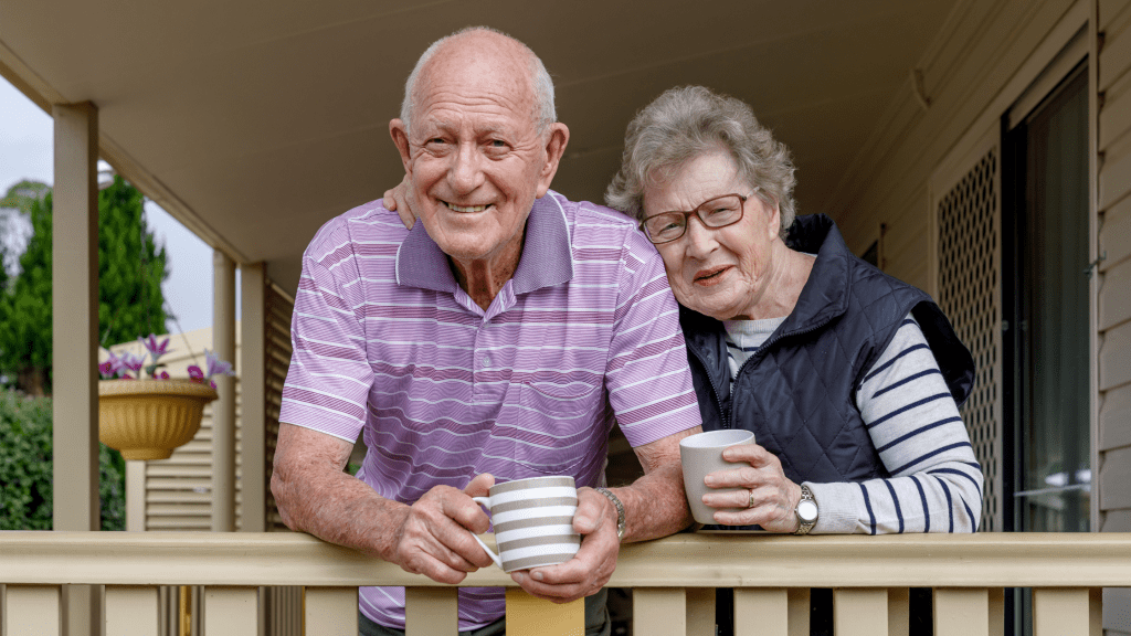 Senior couple on porch smiling and drinking coffee